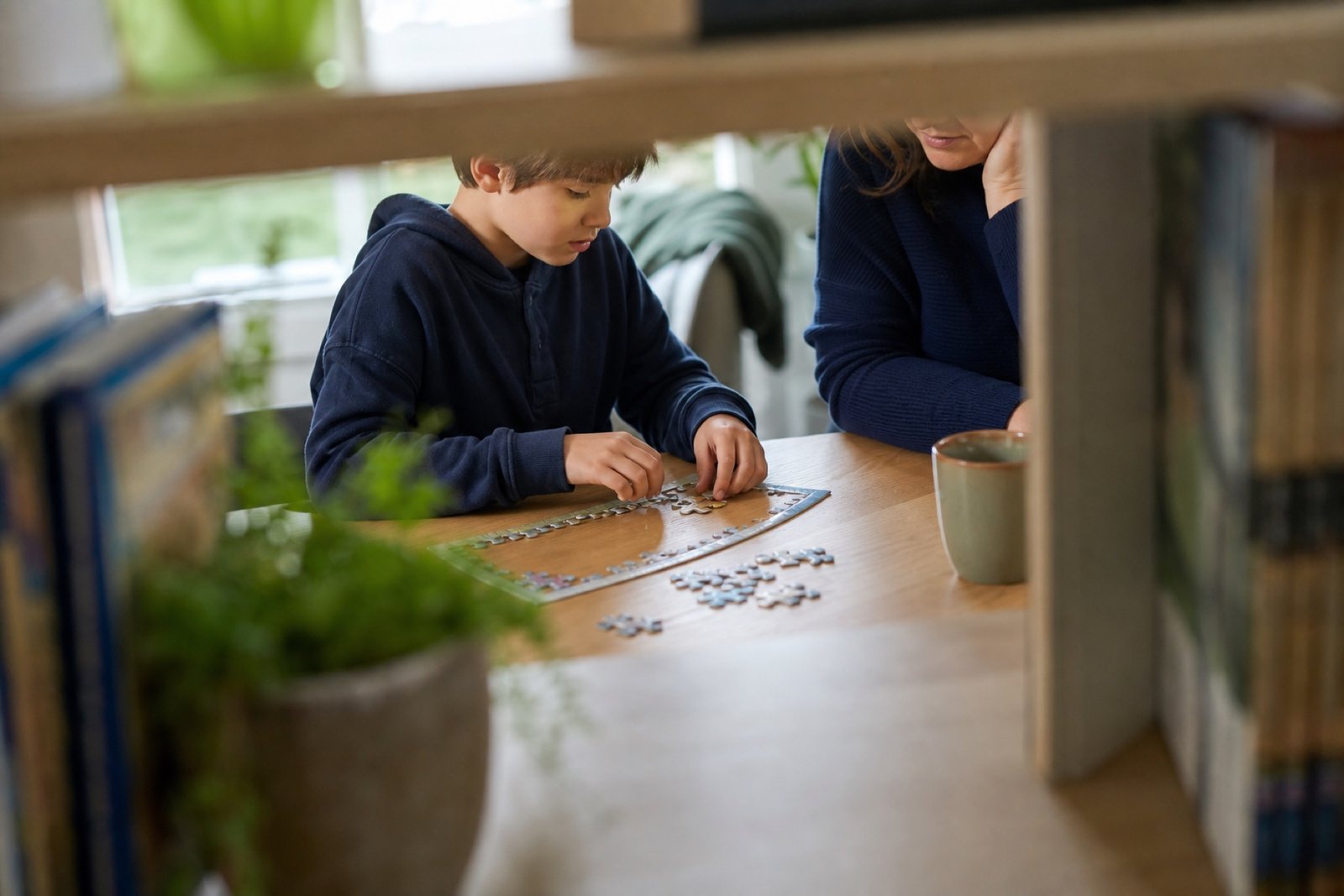 Child completing a focused puzzle with a parent nearby